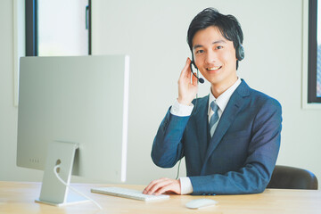 ヘッドセットをつけてインサイドセールスをするスーツ姿の若い男性