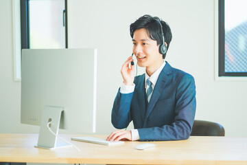 ヘッドセットをつけてインサイドセールスをするスーツ姿の若い男性