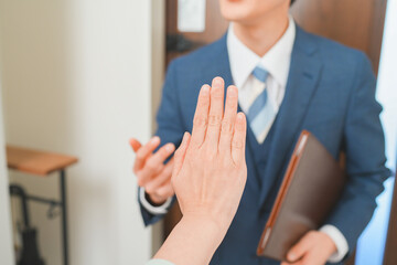 訪問販売を断る主婦と若い営業マンの男性