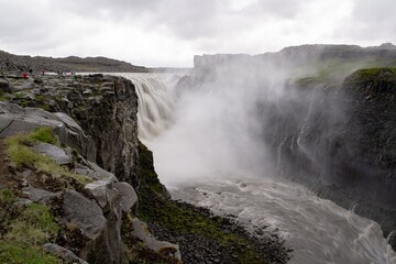 Spectacular Dettifoss waterfall in Iceland after floods filled with muddy water and tourists in raincoats