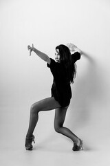 Fototapeta na wymiar Passionate latina dancer in the studio is dancing in small black dress