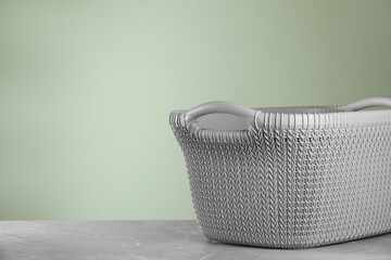 Empty plastic laundry basket near light green wall. Space for text