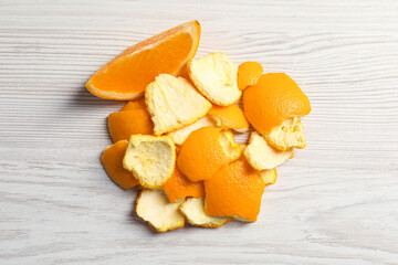 Orange peels preparing for drying and piece of fresh fruit on white wooden table, flat lay