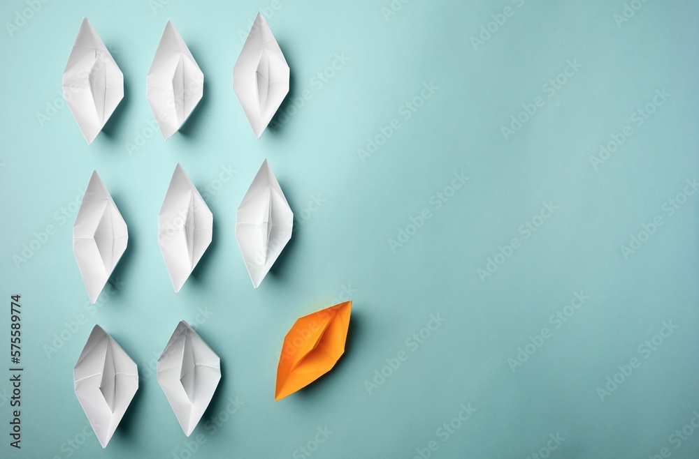 Canvas Prints Yellow paper boat floating away from others on light background, flat lay with space for text. Uniqueness concept