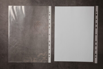 Punched pockets and paper sheet on grey table, top view. Space for text