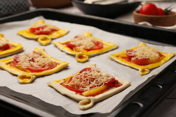 Baking sheet of raw puff pastry with tasty filling on table, closeup