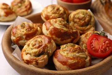 Fresh delicious puff pastry with tasty filling and tomato in wooden bowl, closeup