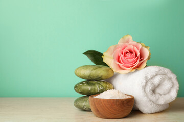 Composition with different spa products and rose on beige table against turquoise background. Space for text