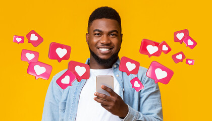 Glad black adult man with beard has romantic chat with hearts on smartphone enjoys message, social...