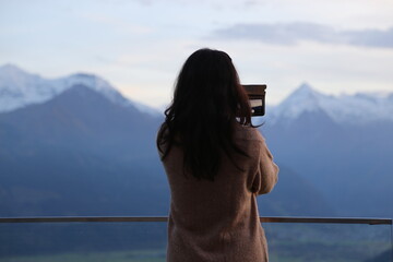woman photographing Alps panorama at dusk