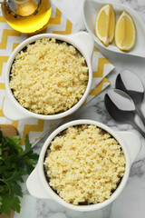 Tasty couscous and ingredients on white marble table, flat lay