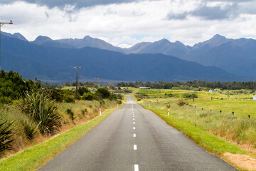 Fototapeta na wymiar Winding and scenic road in New Zealand, with mountains and blue sky