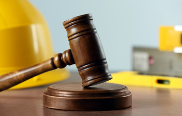 Construction and land law concepts. Judge gavel, protective helmet with levels on grey table