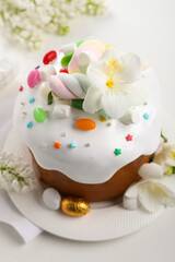 Traditional Easter cake with sprinkles, jelly beans, marshmallows and decorated eggs on white table, closeup