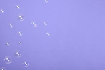 Many beautiful soap bubbles on violet background. Space for text