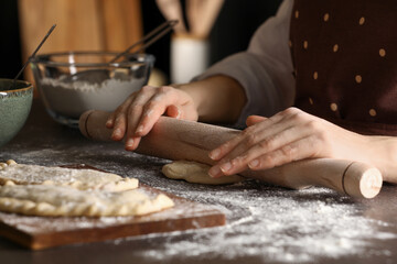 Obraz na płótnie Canvas Woman rolling dough for chebureki at wooden table, closeup
