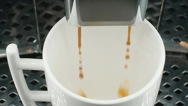 The white cup filling up a coffee from the machine inside the kitchen in Estonia