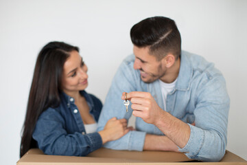 Obraz na płótnie Canvas Relocation Concept. Happy Young Spouses Leaning On Cardboard Box And Holding Keys