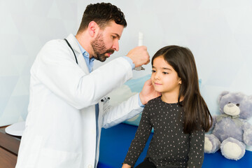 Caucasian pediatrician using a otoscope during a check up