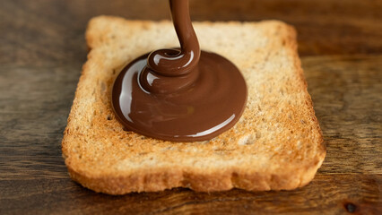 Pouring Сhocolate paste on roasted toast bread. Perfect traditional breakfast