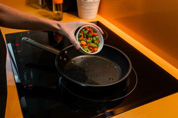 Unrecognizable person throwing vegetables in a frying pan