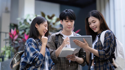 Group of young Asian college students sitting on in front of the school building, talking and focusing on their school project