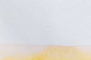 Macro close-up of yellow watercolor paint on a textured white aquarelle paper. High resolution full frame background with copy space.