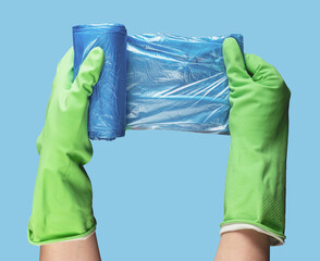 Garbage trash bag roll in hand in green glove, using new polyethylene plastic packages
