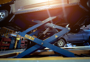 Car on hydraulic lift in auto repair shop