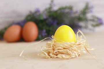 Yellow Easter egg in a nest on a background of flowers. Christ is risen. Easter holiday