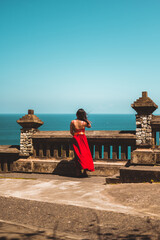 Woman in a red dress looking at the ocean, Uluwatu, Bali, Indonesia