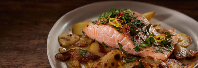 Tasty salmon steak with fried potato slices on plate
