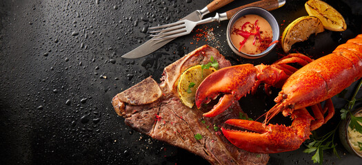 Tasty lobster and beef steak on wet surface
