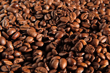 Coffee beans background. Texture of coffee beans close up. Dark brown roasted coffee is spinning. Abundance. Concept for coffee product advertising. Selective Focus. Border design with copy space