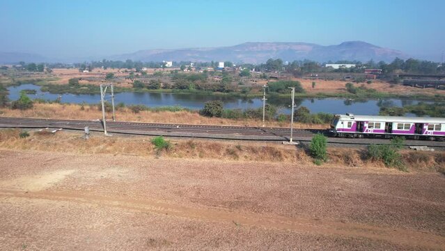 Aerial footage of a local commuter train heading towards Lonavala, at Kamshet near Pune India.