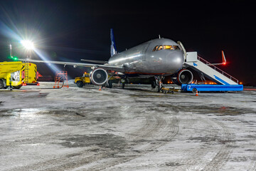 Closeup high detailed view of refueling operation of large widebody passenger aircraft standing on airport's parking place at ground maintenance at night