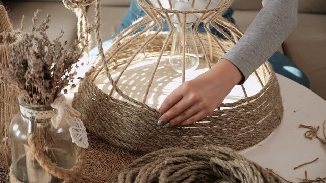 Close up Woman makes handmade diy lamp from jute rope