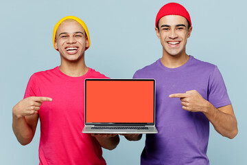 Young fun couple two friends IT men wear casual clothes together hold use work point on laptop pc computer with blank screen workspace area isolated on pastel plain light blue cyan background studio.