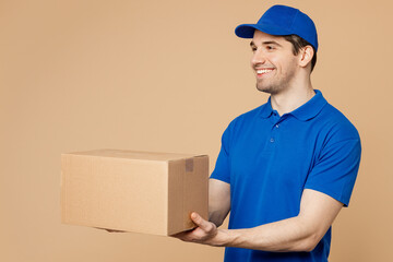 Side view professional happy delivery guy employee man wear blue cap t-shirt uniform workwear work...
