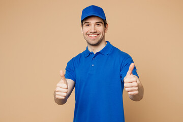 Professional satisfied delivery guy employee man wear blue cap t-shirt uniform workwear work as dealer courier showing thumb up like gesture isolated on plain light beige background. Service concept.