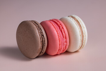 Cookies multicolored macaroons on a pink background of pink, dark brown and beige with shadows