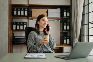 Working woman concept a female manager attending video conference and holding tablet, smatrphone and  cup of coffee in office....