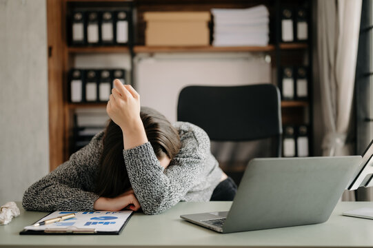  woman feeling migraine head strain.Overworked businesswoman financier while working on laptop and tablet at office.