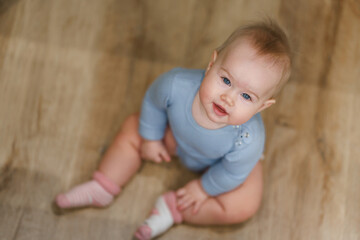 Portrait of charming Caucasian baby toddler with blue eyes in home in children room