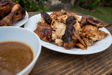 A plate of chopped Lechon Manok, or roasted chicken served outside at a bench with gravy.