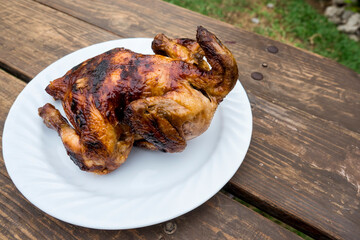 A plate of Lechon Manok, or roasted chicken served outside at a bench.