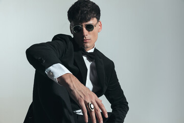 Obraz premium stylish young businessman in black tuxedo holding elbow on knee