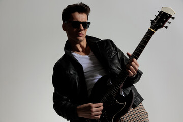 handsome sexy man with glasses playing guitar and being cool