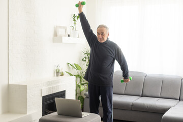 Gray-haired senior man doing online training on a laptop