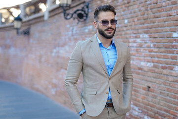 Obraz premium sexy bearded businessman looking away and holding hands in pockets
